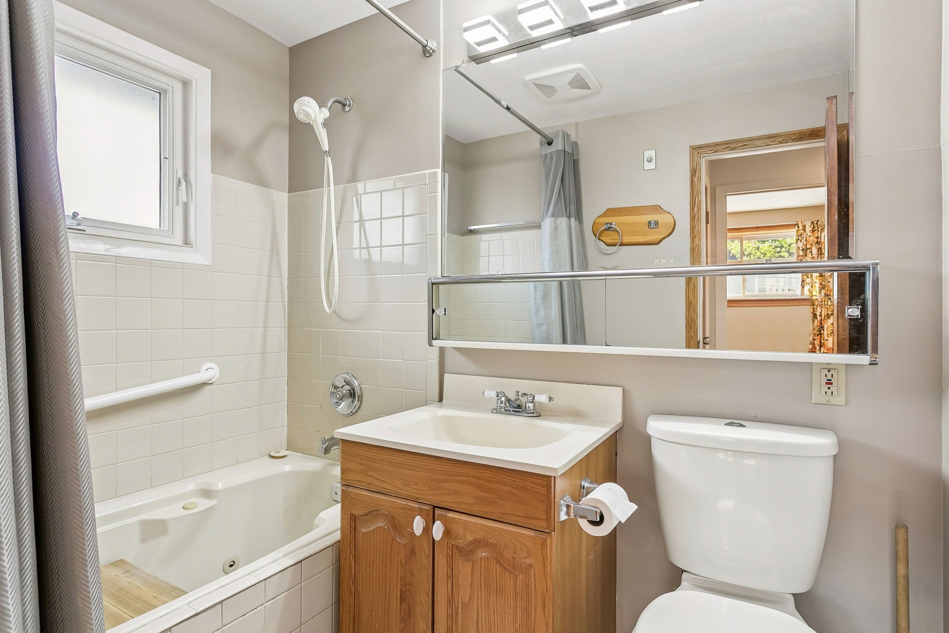 Bright bathroom with tub, vanity, and large mirror