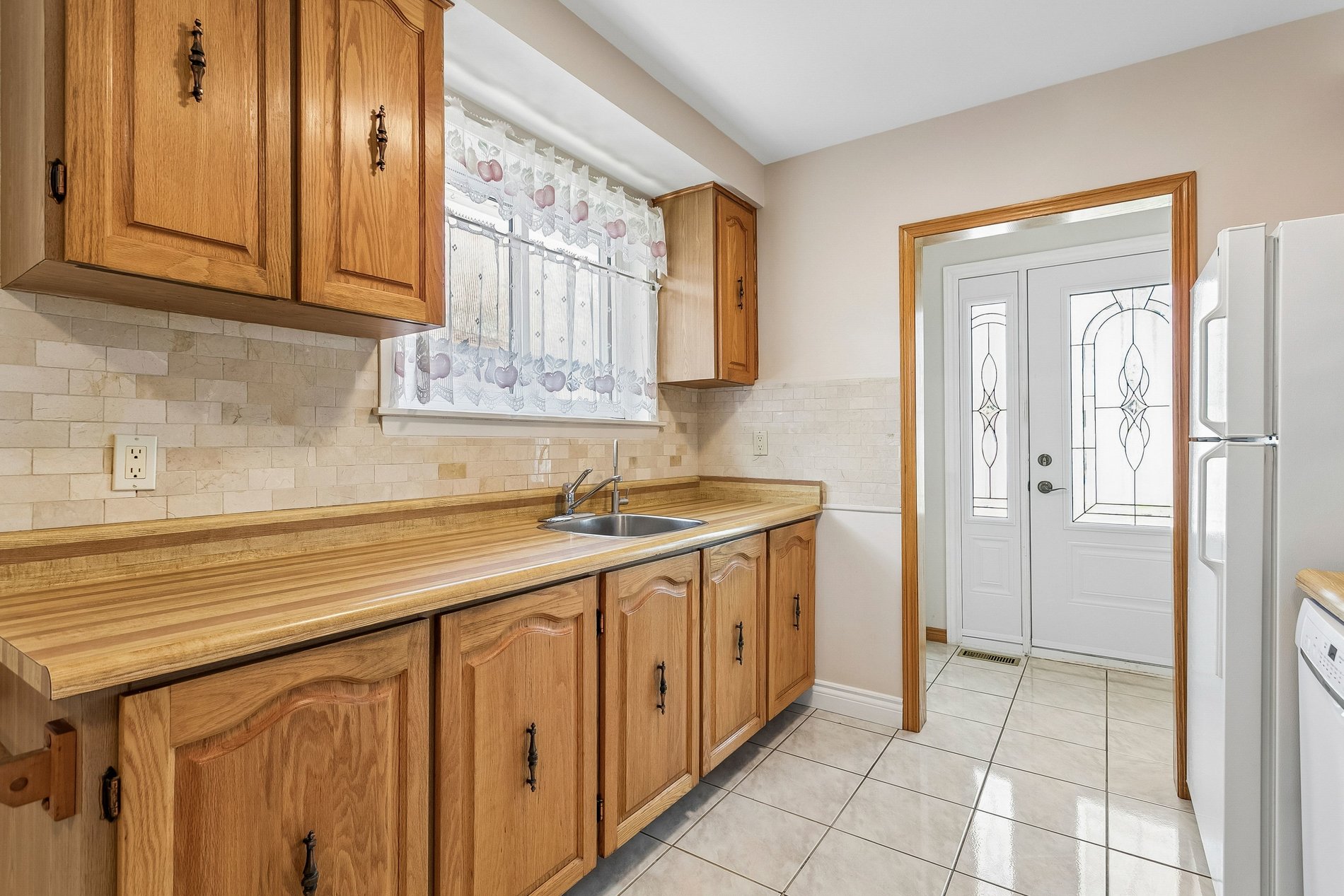 Galley kitchen with wood cabinetry and tiled flooring
