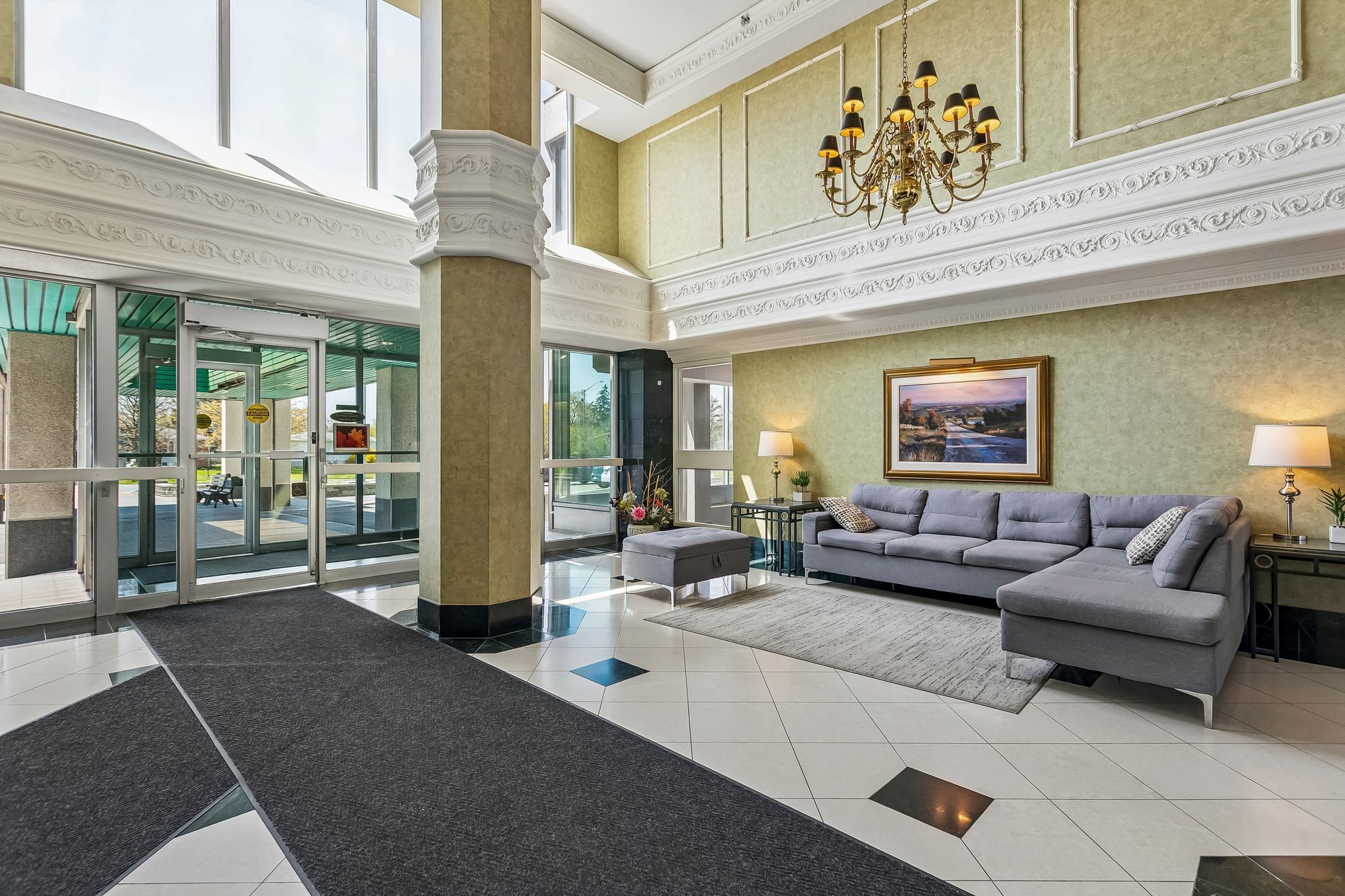 Elegant condo lobby with high ceilings, chandelier, and lounge seating