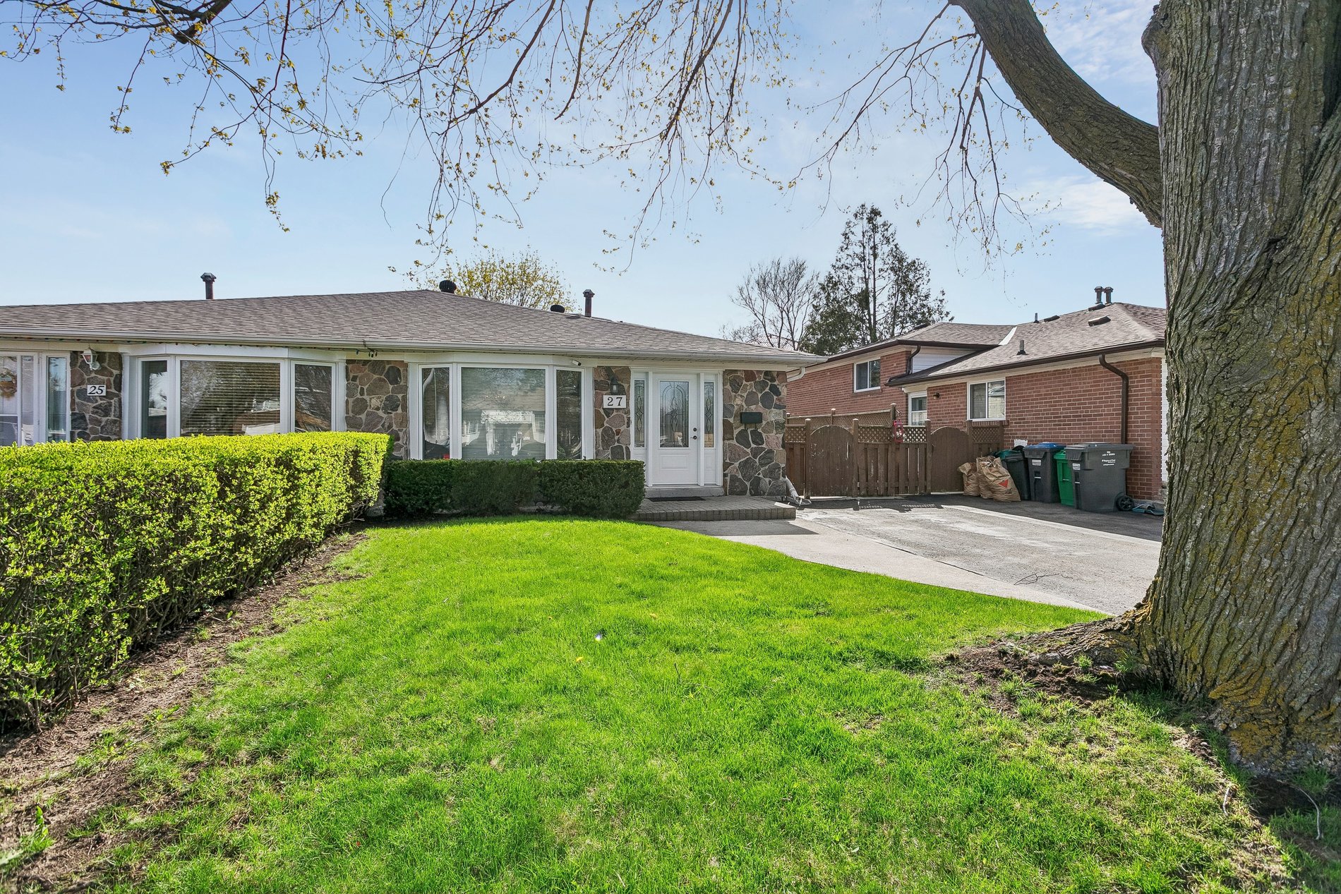 Front view of a semi-detached home with a large front lawn and driveway