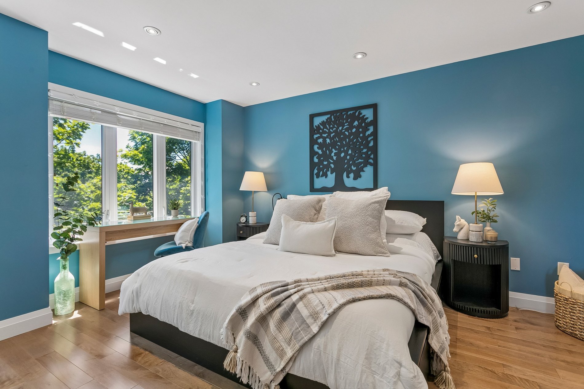 Staged bedroom with blue accent walls, workspace, and natural light