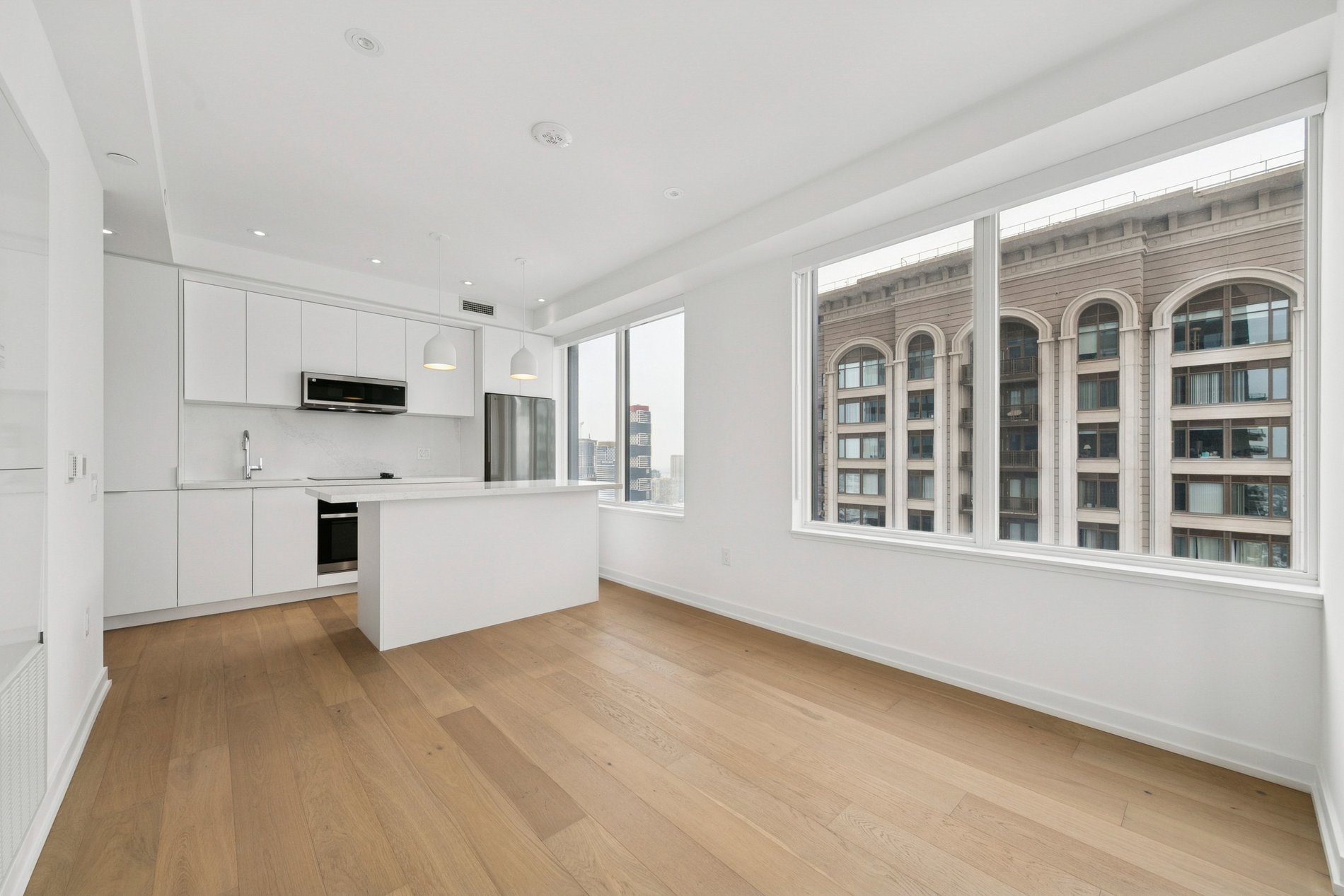 Bright modern condo with white kitchen, island, and floor-to-ceiling windows