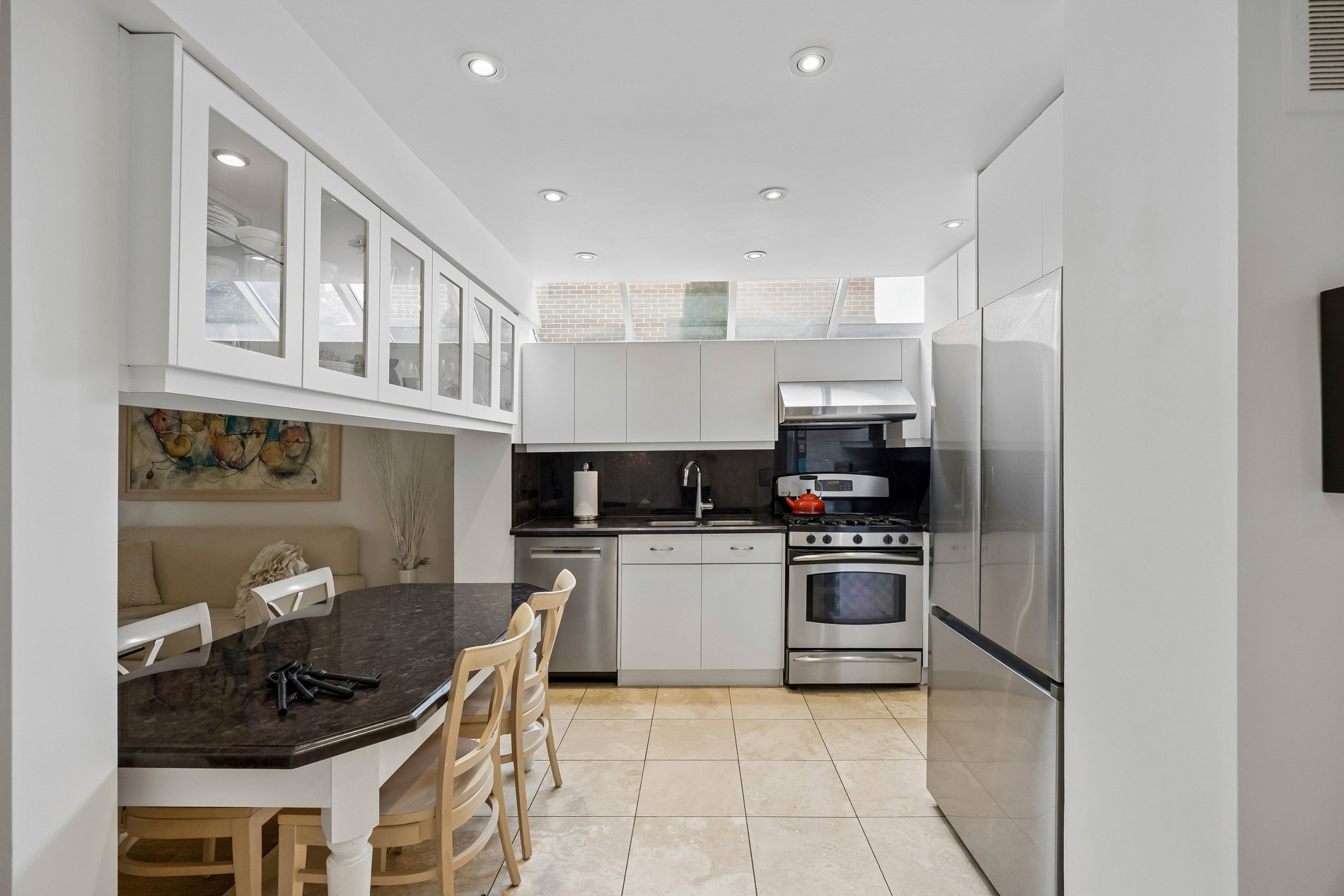 Modern white kitchen with stainless steel appliances and breakfast bar