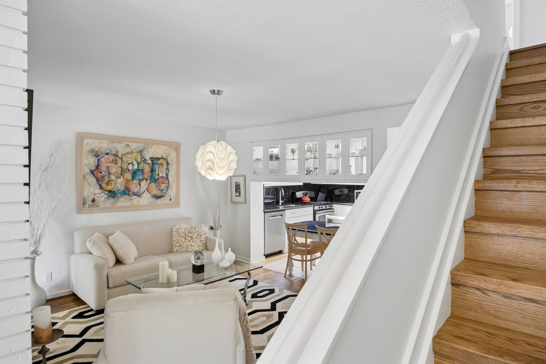 Open-concept living room and kitchen with hardwood stairs and modern finishes