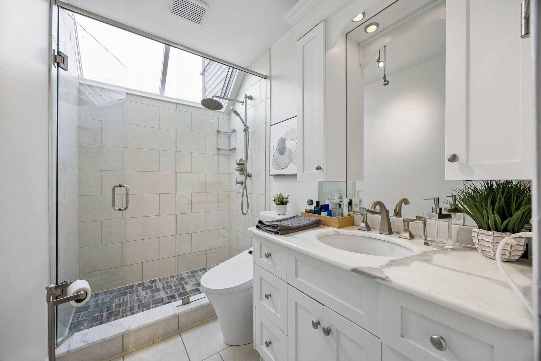 Modern white bathroom with glass walk-in shower and marble vanity