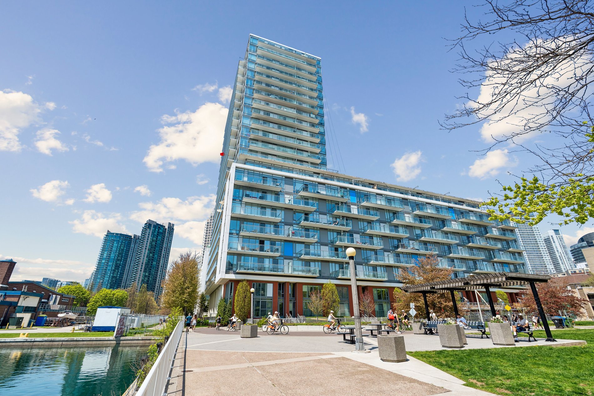 Modern waterfront condominium building with glass balconies and landscaped public plaza